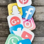 Közösségi média ikonok faháttéren, köztük Facebook, Instagram, Twitter és LinkedIn.